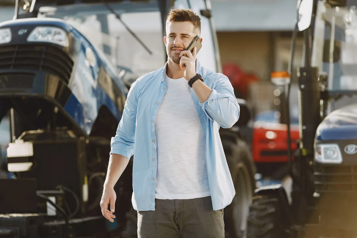 Boer belt met zijn telefoon, voor de trekker langs